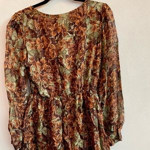Short dress with long sleeves with a jungle meets fall pattern .